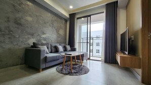 A modern living room with a grey sofa, a round coffee table, and a flat-screen TV on a wooden stand.
