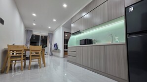 A modern kitchen with a built-in microwave, a refrigerator, and a dining area with wooden chairs and a table.