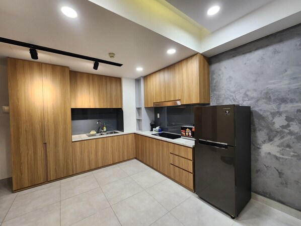 Eine moderne Küche mit Holzschränken, einem schwarzen Kühlschrank und einem gefliesten Boden.