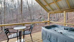 Eine Holzterrasse mit Whirlpool, zwei Stühlen und einem Tisch.