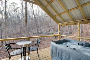 Une terrasse en bois avec un jacuzzi, deux chaises et une table.