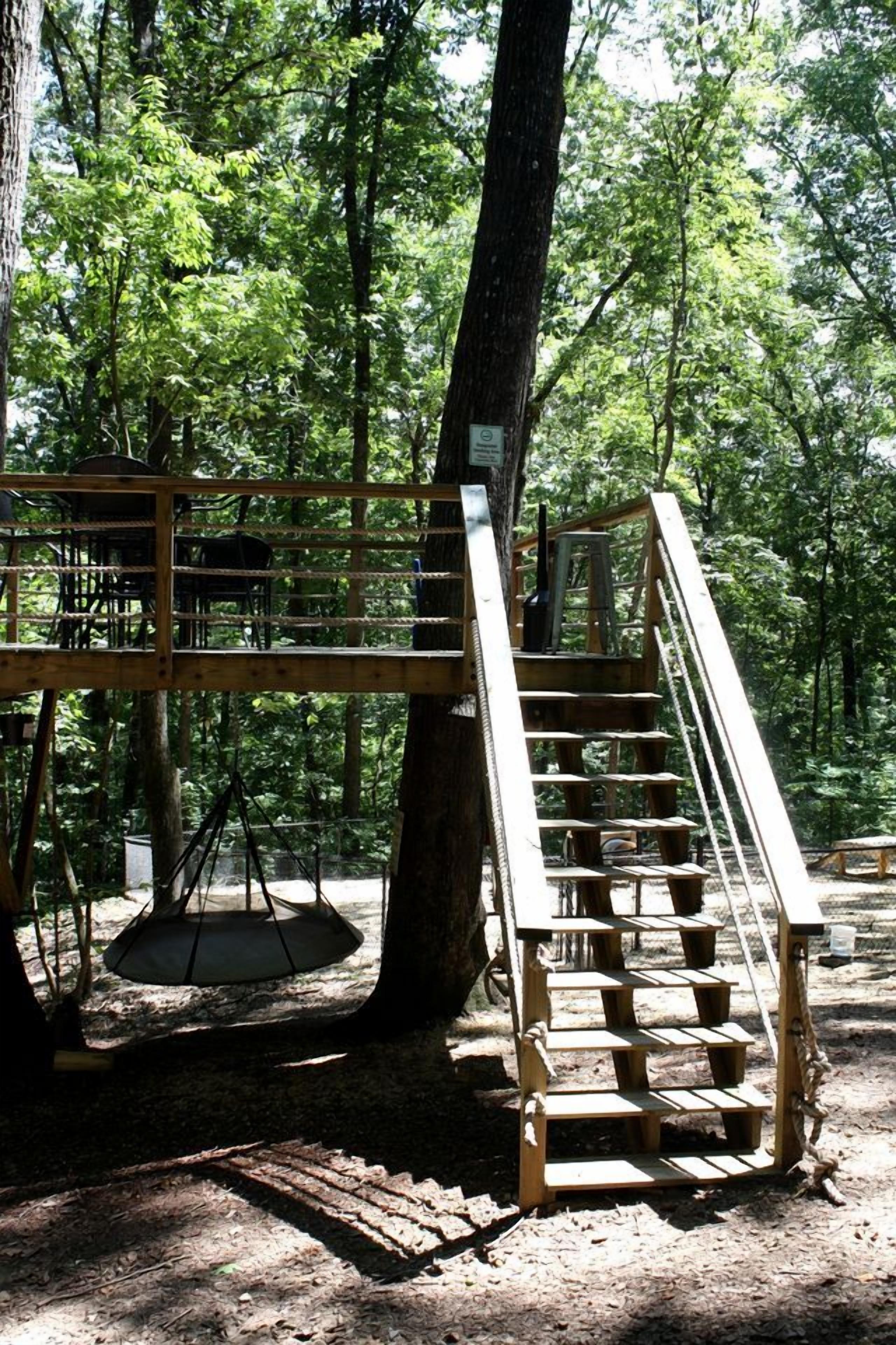 A wooden staircase leading up to a platform in a forested area.