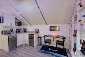 A compact kitchen with a microwave, toaster, and dishwasher. There is a small dining area with a table and chairs.