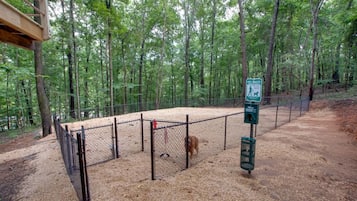 A fenced outdoor area with a pet waste station, surrounded by trees.