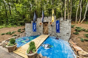 A stone building with a wooden deck and a swimming pool with a mural.
