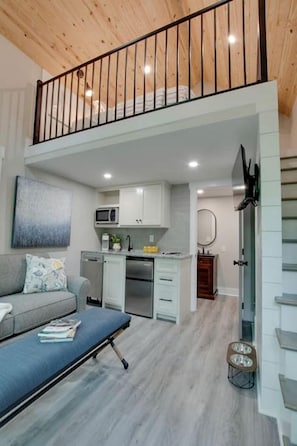Un apartamento moderno con un área de estar tipo loft, una kitchenette y un comedor.