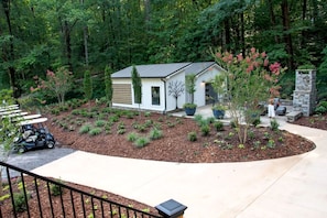 A residential property with a small house, a driveway, a golf cart, and a landscaped garden.