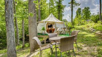 A tent with a table and chairs in a forested area.