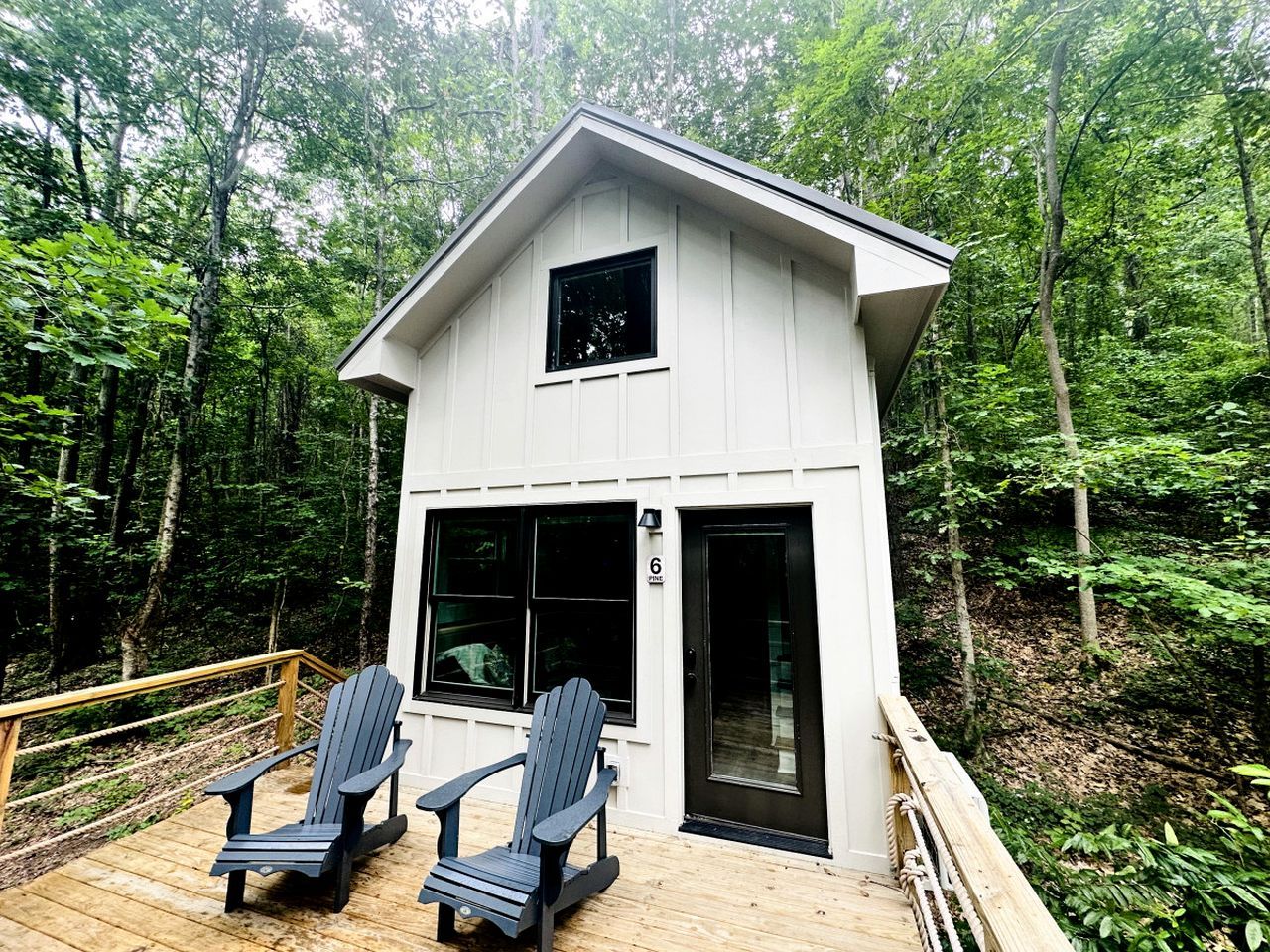 Une petite cabane dotée d’une terrasse, de deux fauteuils Adirondack et d’une porte portant un numéro.