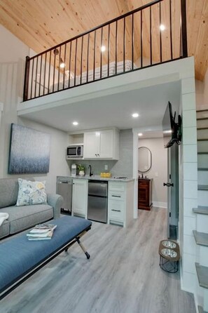 A modern apartment with a loft-style living area, a kitchenette, and a dining area.