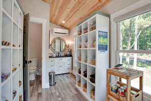 A bathroom with a toilet, sink, vanity, and shelves with various items. - Amazing Tree House Perfect for a Secluded Getaway in Alabama (Scottsboro)