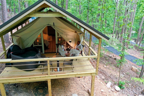 A wooden cabin with a pitched roof, a covered porch, and a tented interior.