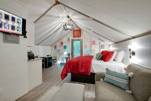 Ein Zelttraum mit Bett, Sofa, Schreibtisch und Fernseher.