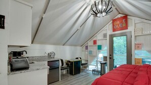 Une pièce aménagée comme une tente, avec un coin cuisine, un lit et un panneau indiquant « PARTIE TERMINÉE ».