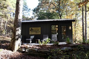 Een klein gebouw met een bord waarop 'Leaf & Stone Spa' staat, en twee rieten stoelen ervoor.