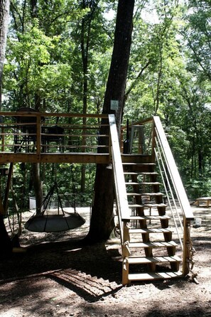 A wooden staircase leading up to a platform in a forested area. - Pet-Friendly Tree House Great for a Relaxing Escape in Alabama (Scottsboro)