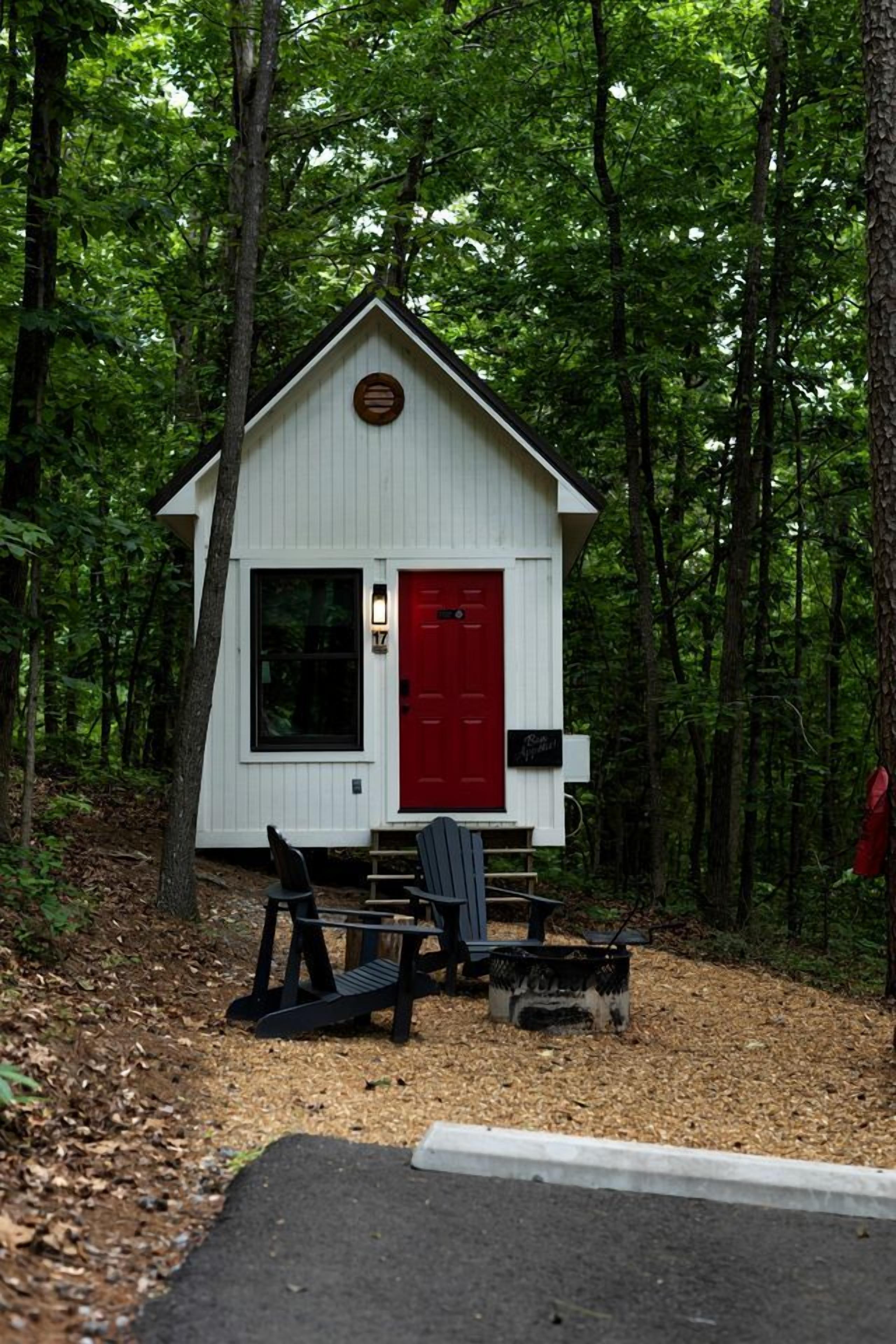A small cabin with a red door, surrounded by trees.