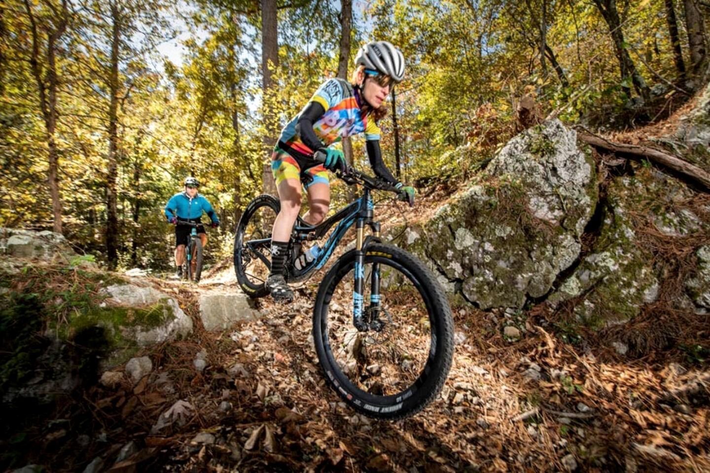 A mountain biker navigating a rocky trail in a forested area.