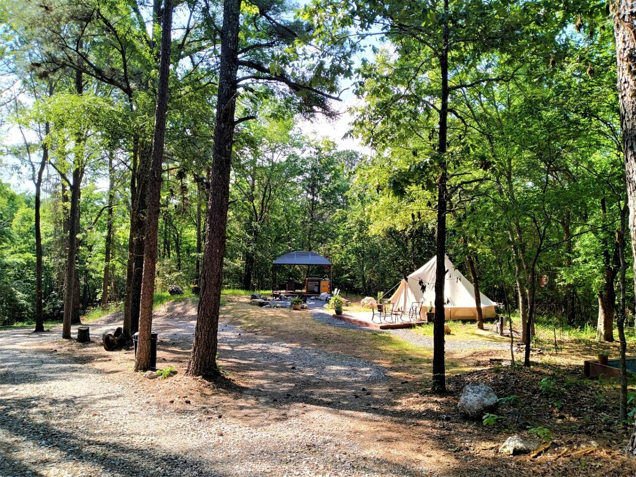 Um camping com uma tenda, uma mesa de piquenique coberta e uma área de churrasco.