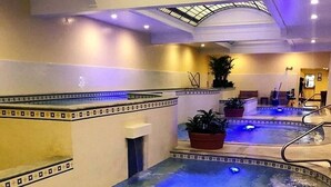 Ein Innenpool mit Dachfenster, gefliesten Wänden und Topfpflanzen.