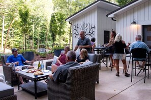 An outdoor patio area with wicker furniture, a table with food and drinks, and a building with a tree mural. - Breathtaking Treehouse with Barbecue and Hot-tub in Scottsboro, Alabama (Scottsboro)