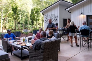 An outdoor patio area with wicker furniture, a table with food and drinks, and a building with a tree mural.