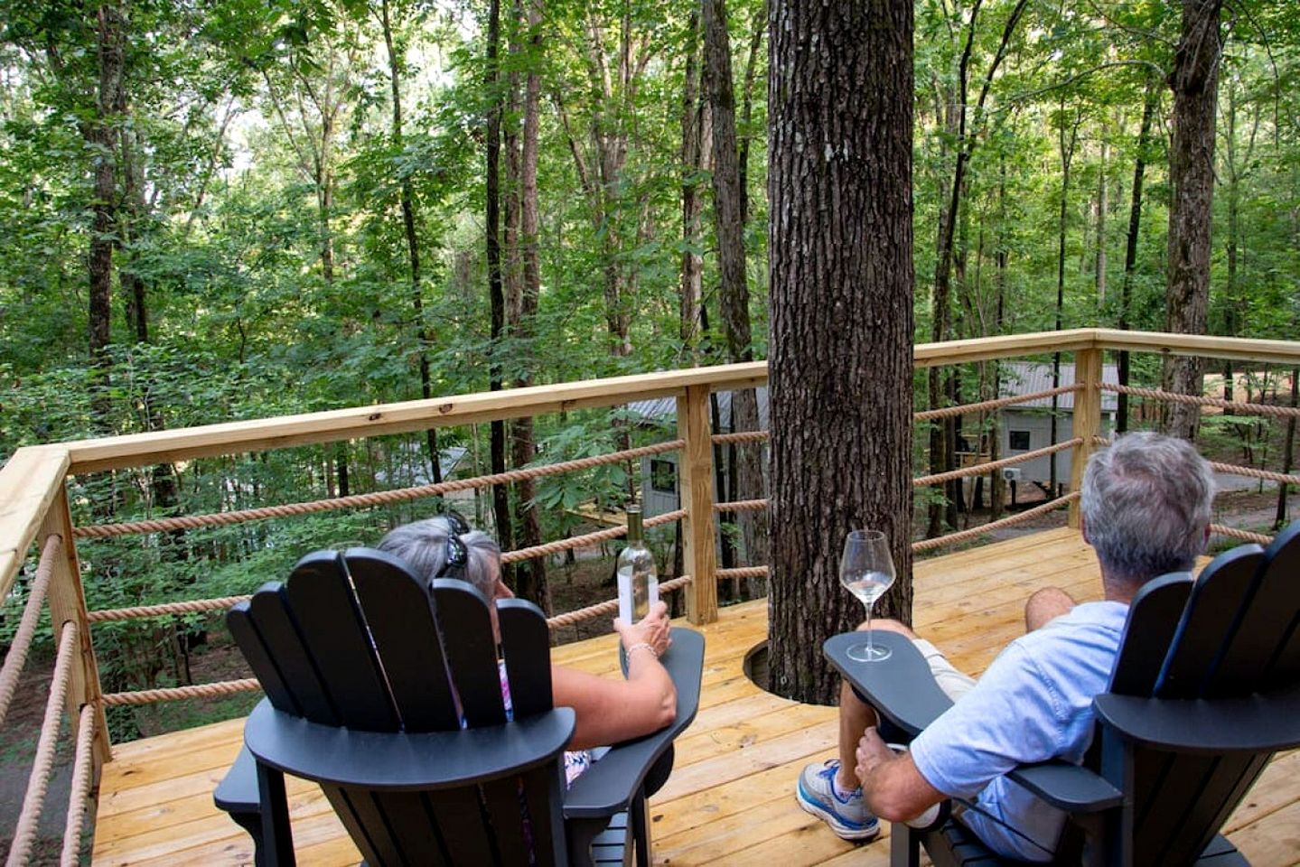 A wooden deck with rope railings overlooking a forest.