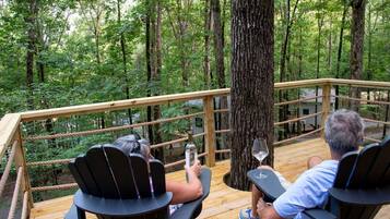 A wooden deck with rope railings overlooking a forest.