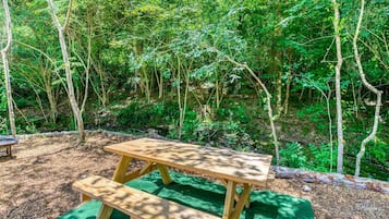 A picnic table with a bench in a forested area.