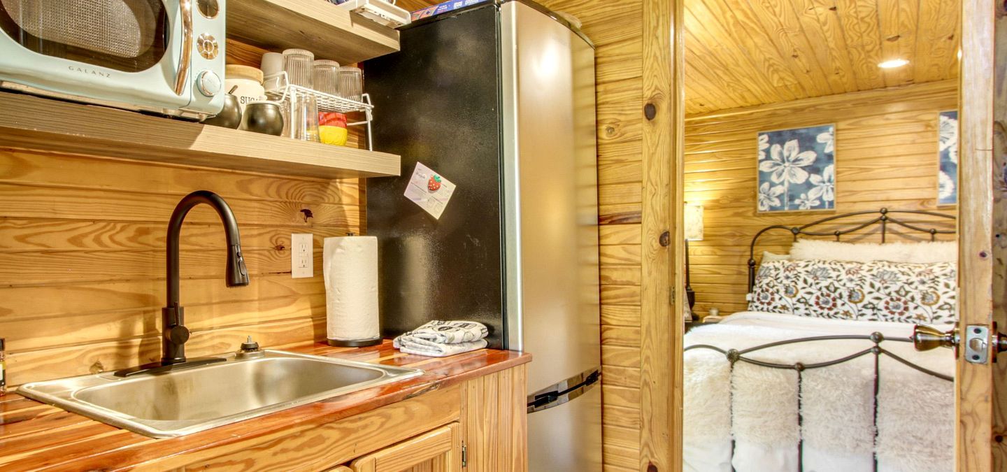 Una cabaña de madera acogedora con kitchenette, que incluye un lavamanos, un microondas y un refrigerador.