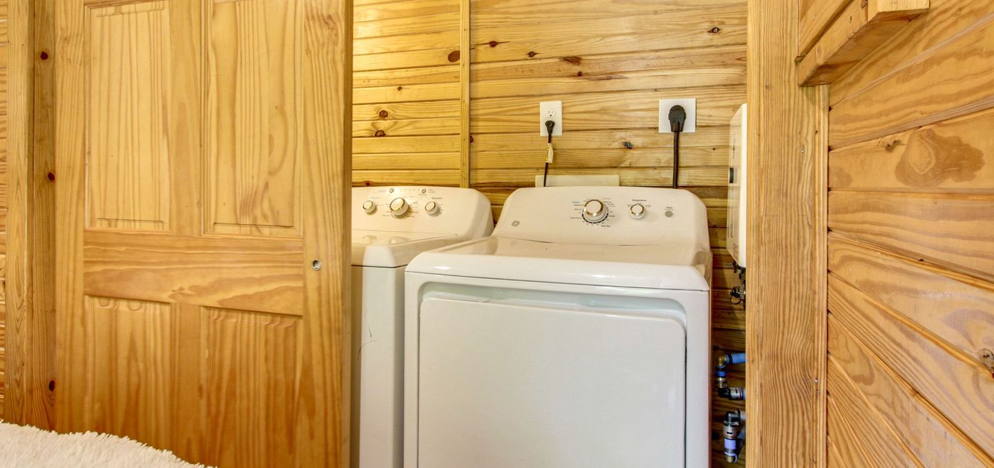 A laundry room with wooden walls and a white washing machine.