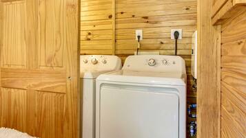 A laundry room with wooden walls and a white washing machine.