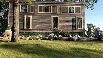Ett tvåvåningshus byggt av trä, med en ytterdörr, fönster och en liten trädgård.