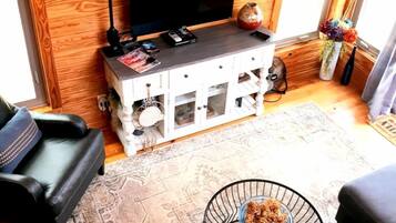 A living room with a TV, wooden wall paneling, a sofa, a coffee table, and a decorative vase.