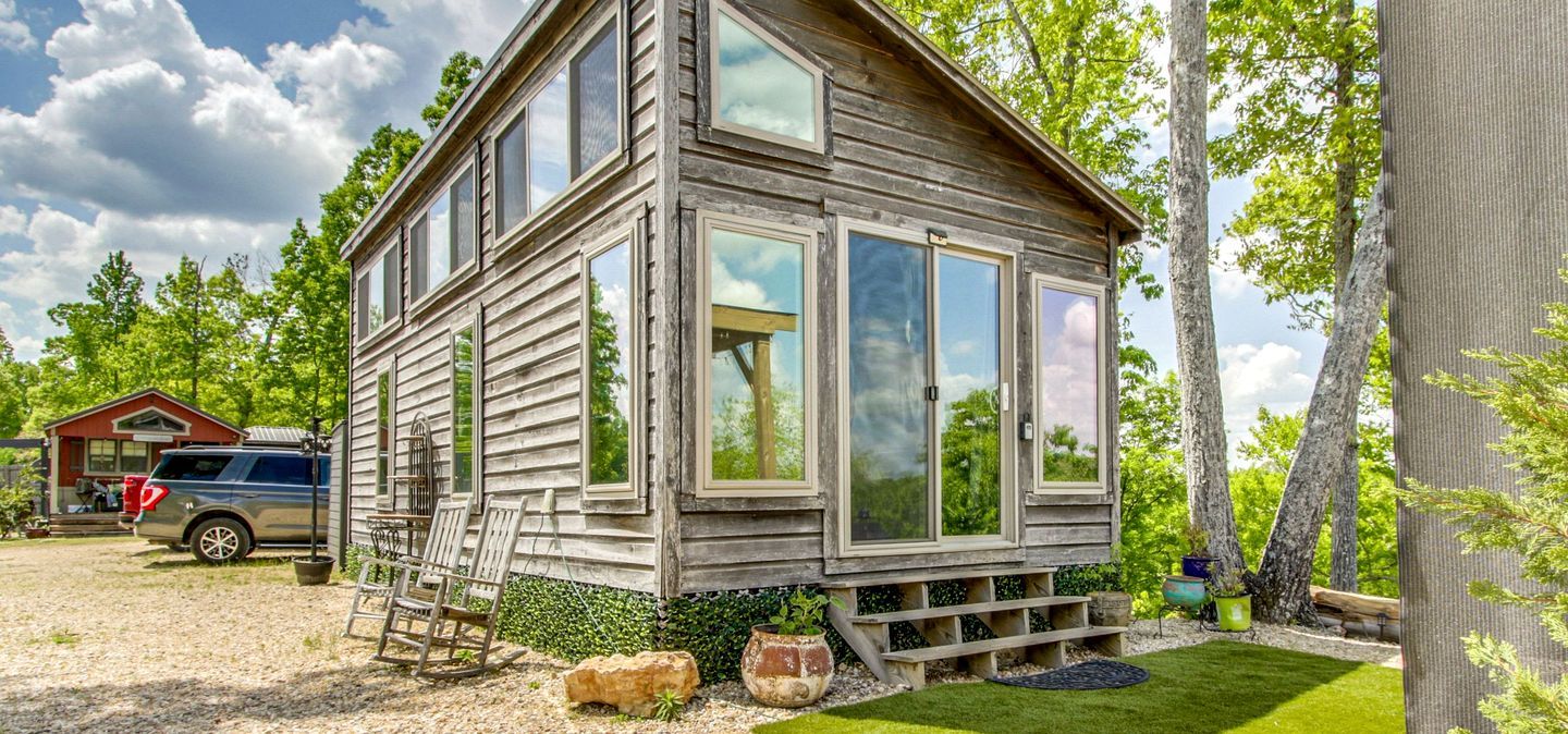 Ein rustikales Holzhaus mit Veranda, einer Leiter und einem kleinen Garten.