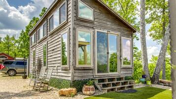 Ein rustikales Holzhaus mit Veranda, einer Leiter und einem kleinen Garten.