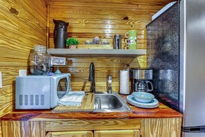 Una cocina compacta con microondas, cafetera y lavabo.