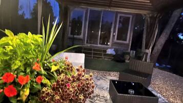 An outdoor seating area with a table and chairs, surrounded by potted plants and a view of the night sky.