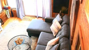 A cozy cabin interior with a sectional sofa, a small round table with a bowl, and a ceiling fan.