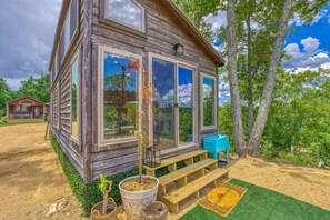 Eine rustikale Holzhütte mit großen Fenstern, einer kleinen Veranda und einer blauen Sitzgelegenheit im Freien.