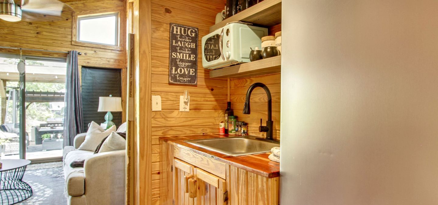 Una cocina acogedora con armarios de madera, un microondas de estilo vintage y un fregadero.