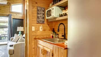 Una cocina acogedora con armarios de madera, un microondas de estilo vintage y un fregadero.