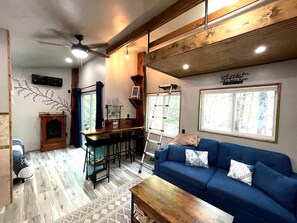 Ein gemütliches Wohnzimmer mit einem blauen Sofa, einem Holztisch und einem Kamin.