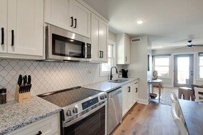 A modern kitchen with white cabinetry, a stainless steel microwave, a built-in oven, and a gas stove.