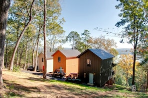 Eine Holzhütte mit einem Metalldach, umgeben von Bäumen, und ein Feldweg, der zur Hütte führt.