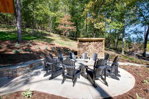 Un patio exterior con sillas Adirondack, un brasero y una pila de leña.