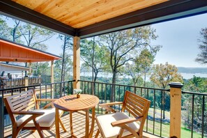 Eine Holzterrasse mit Tisch und Stühlen, mit Blick auf eine malerische Landschaft aus Bäumen und Wasser.