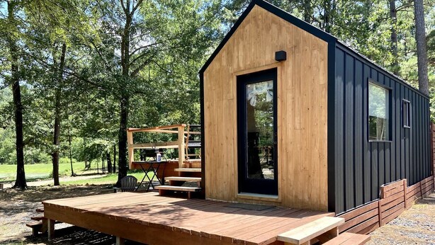 Une petite cabane en bois dotée d’une terrasse, d’un banc et d’une table.