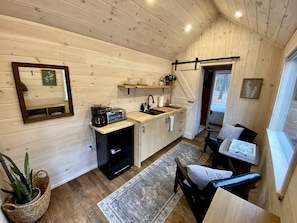A compact kitchen with wooden cabinets, a sink, and a small dining area with a chair and table.