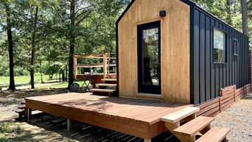 A small wooden cabin with a deck, a bench, and a table.